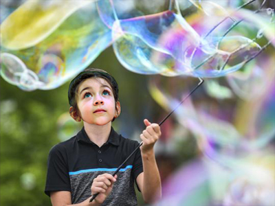 Picture of a young boy playing with a large bubble wand
