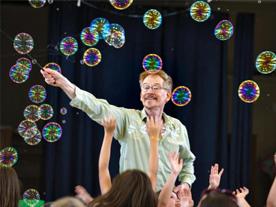 Picture of Steve Couch creating bubbles in front of an audience of children