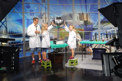 Children touching van de graaff generator on newscast